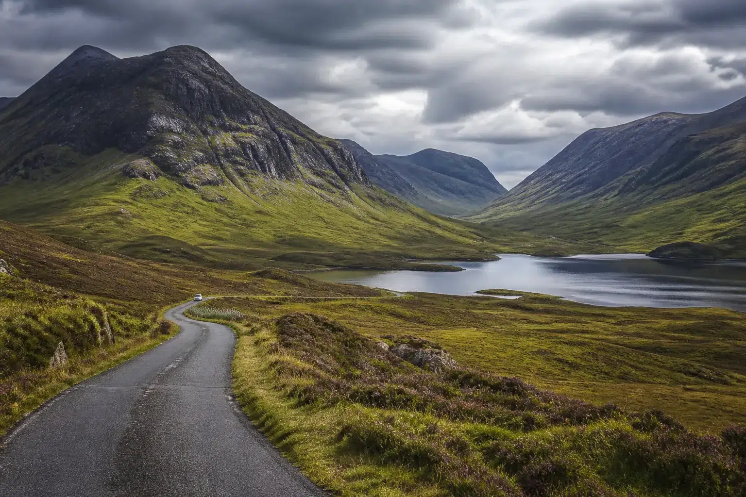 Route dans une vallée des Highlands sous un ciel nuageux